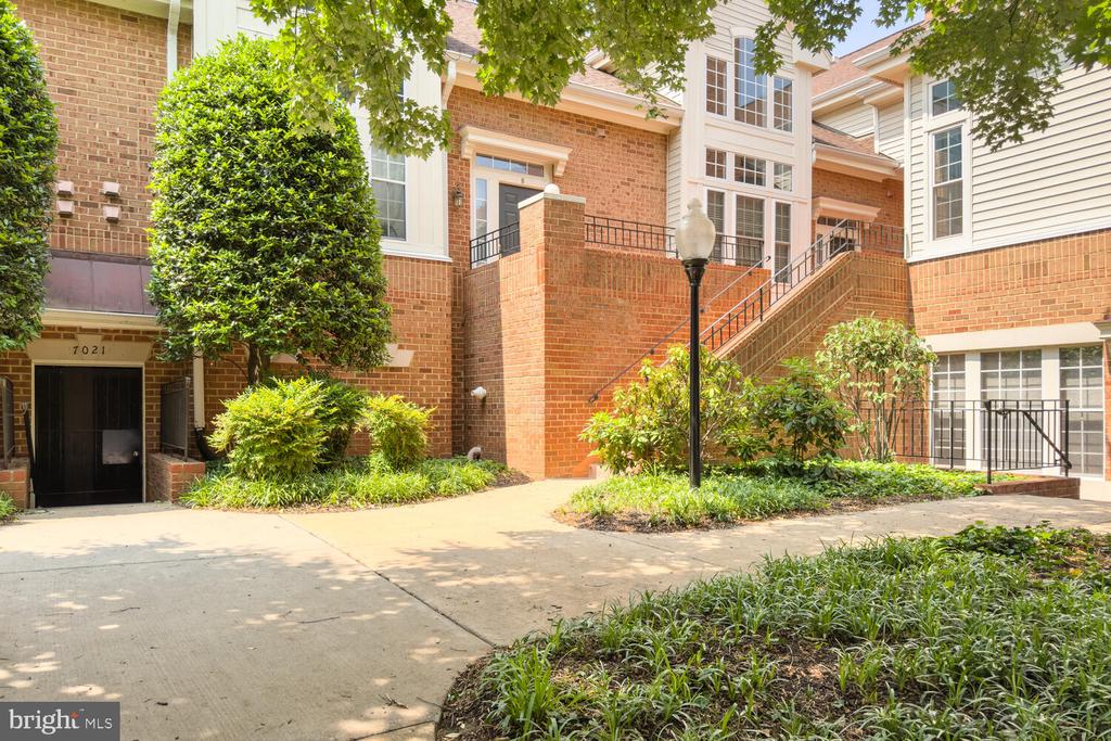 Red-brick residential building with a raised entrance, black railings, and landscaped grounds.