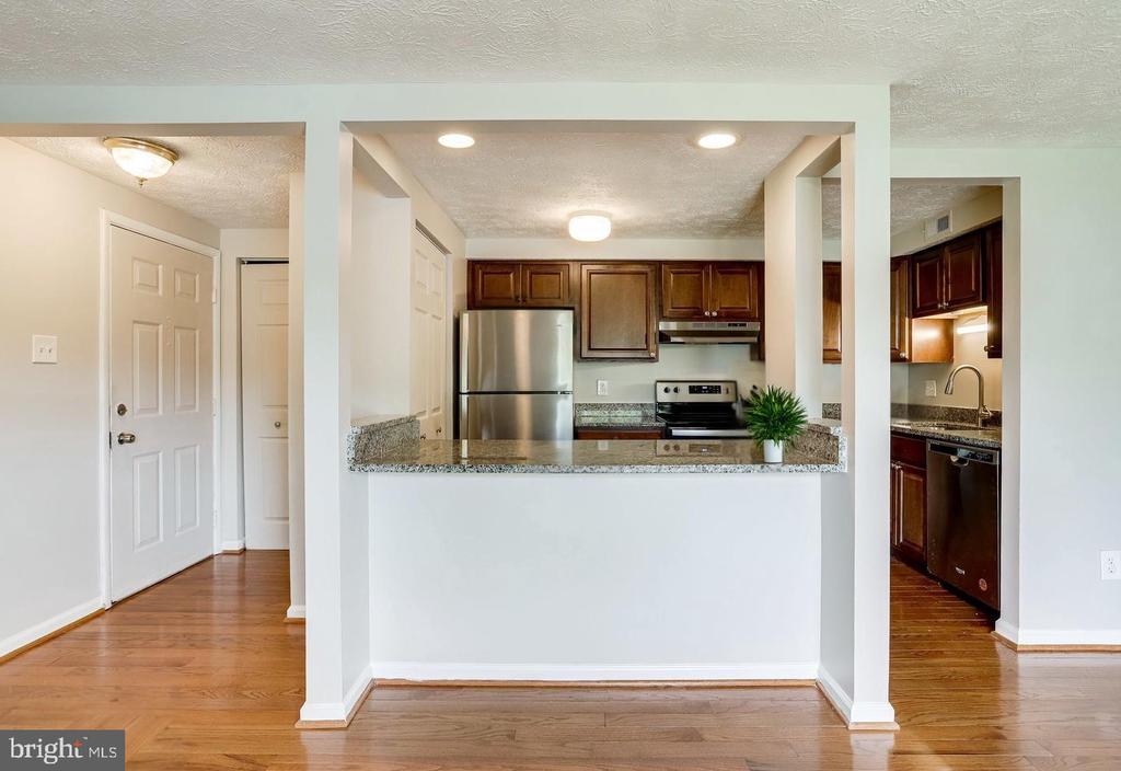 Kitchen with granite breakfast bar, dark cabinets, and stainless steel appliances.