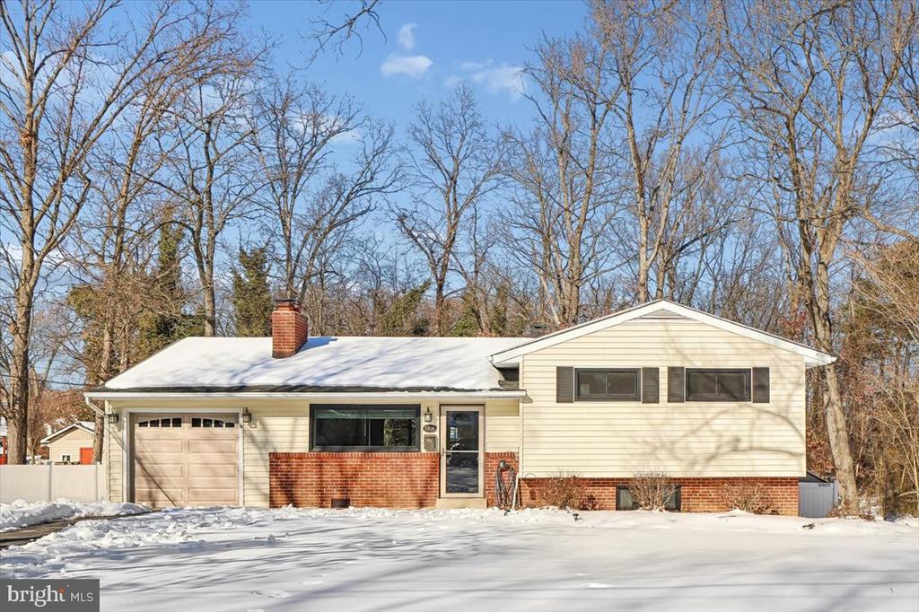 Cream-sided split-level home with a brick facade and snow-covered front yard.