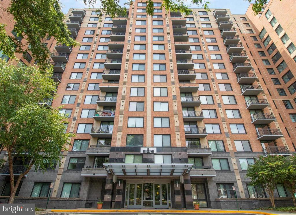 Midtown apartment building with stacked balconies and a glass-canopy entrance.