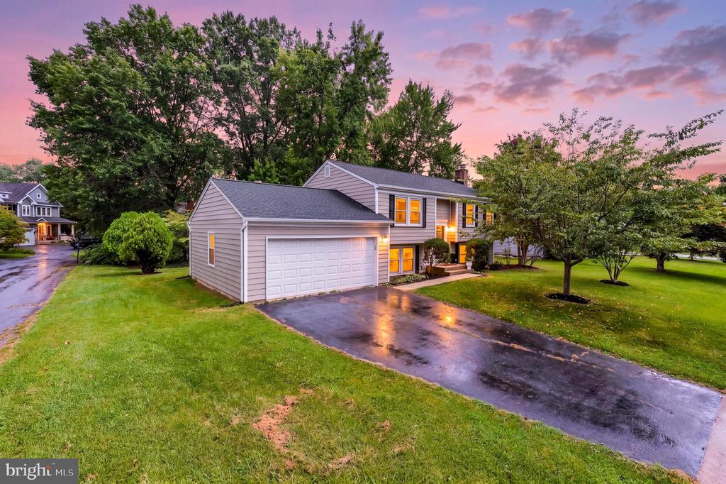 Two-story gray house with an attached garage and wet driveway at dusk.