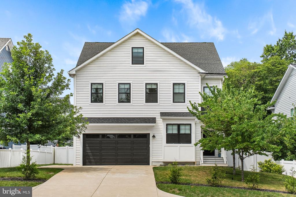 Two-story white house with a front gable, black-framed windows, and a wide two-car garage.