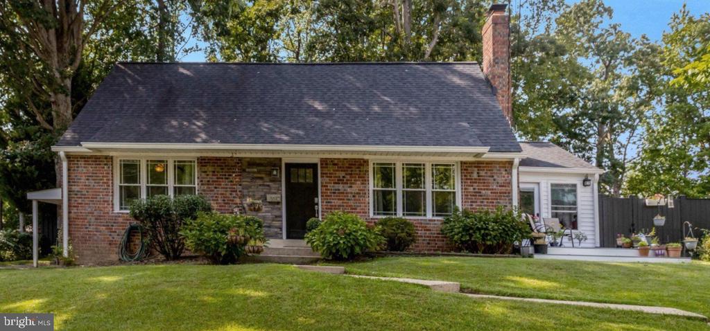 Brick house with a steep dark roof, white-sided addition, and broad green lawn.