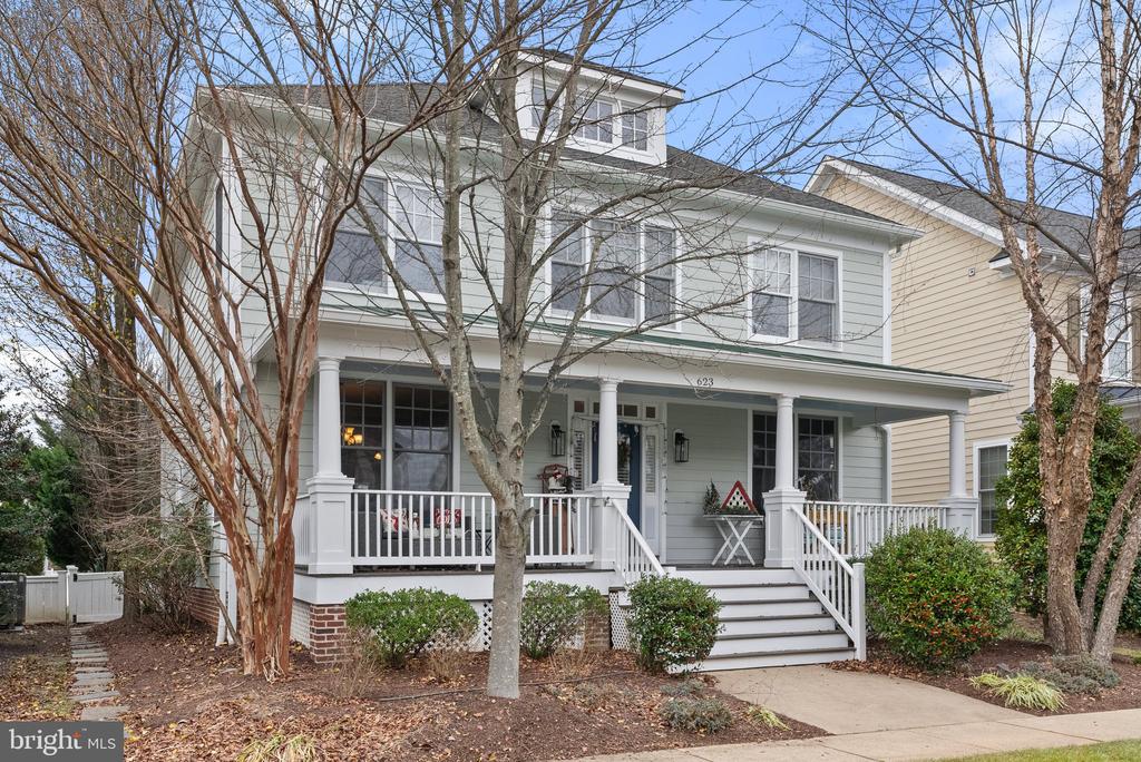 Two-story gray house with a covered white porch, broad steps, and leafless trees.