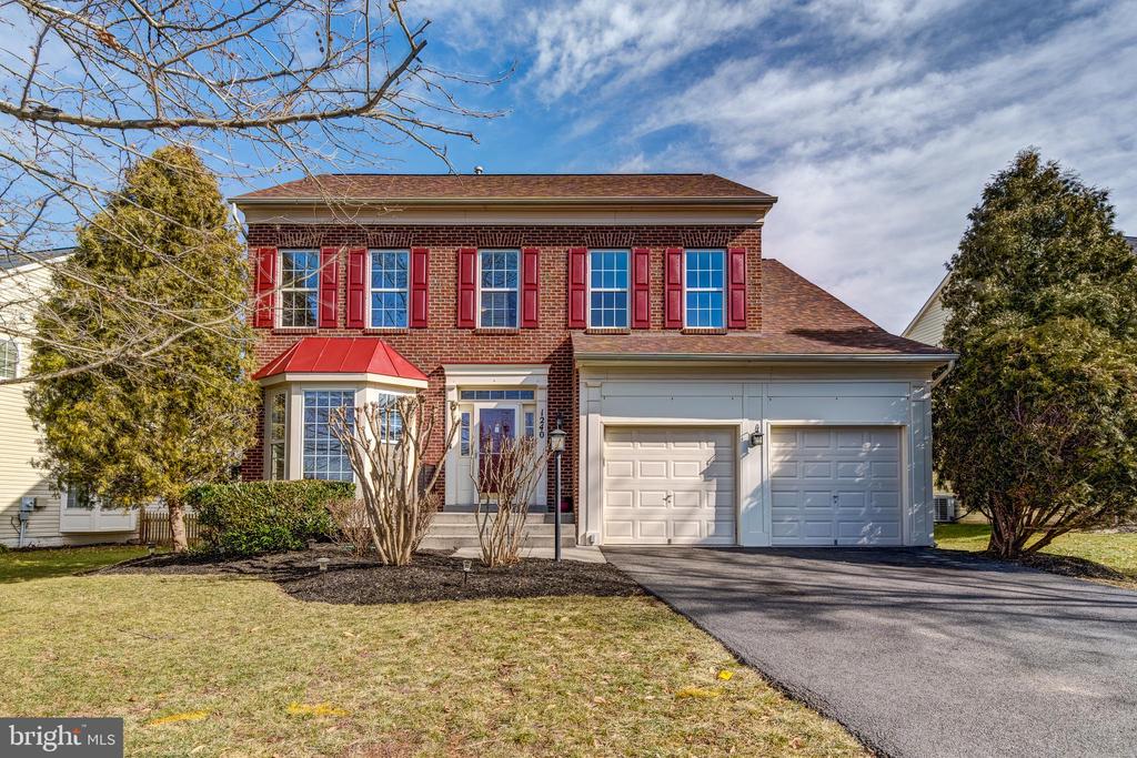 Two-story brick house with red shutters, a bay window, and an attached two-car garage.