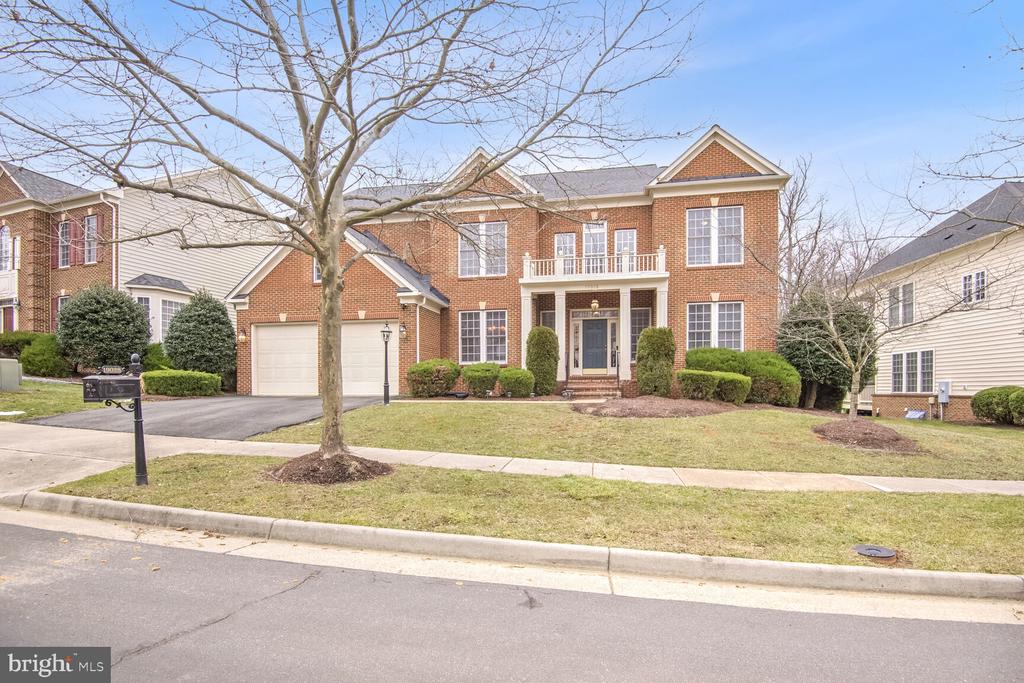 Two-story brick house with a double garage and balcony, viewed from the street.