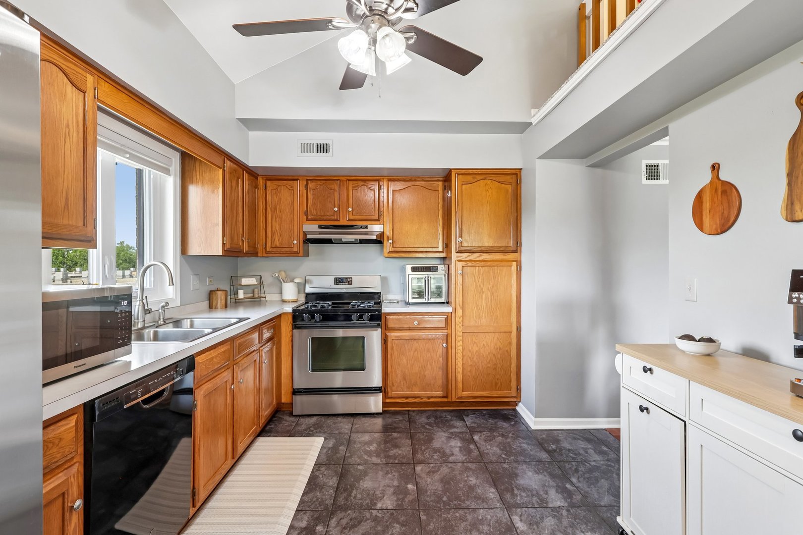 Kitchen with warm wood cabinets, stainless steel appliances, and a sink beneath a window.