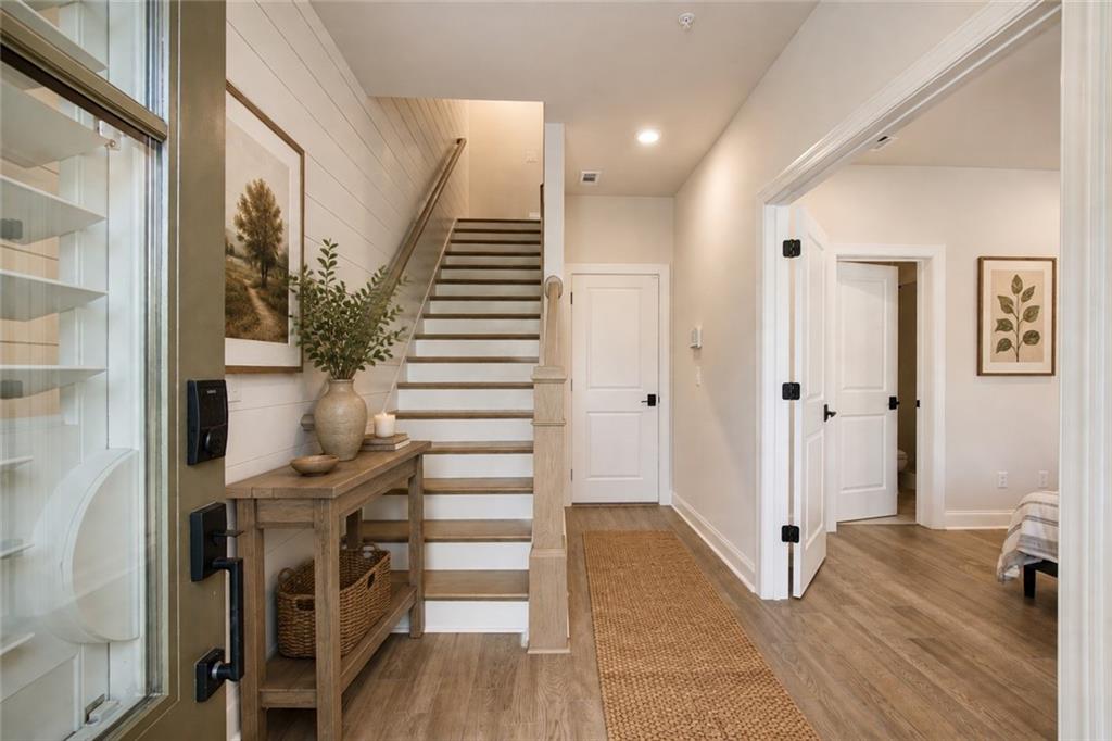 Entryway with a wood-and-white staircase, console table, and woven floor runner.