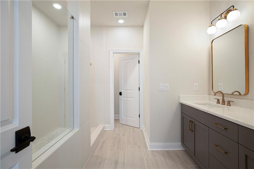 Bathroom with a glass shower and dark vanity beneath a large framed mirror.