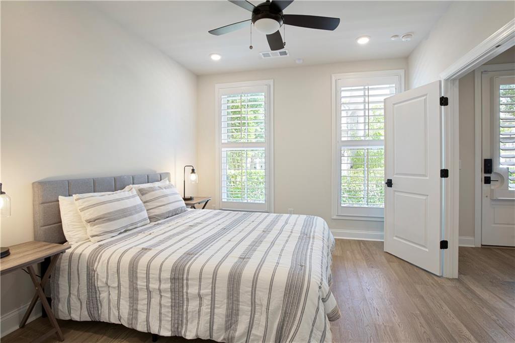 Bedroom with striped bedding, shuttered windows, and a ceiling fan.