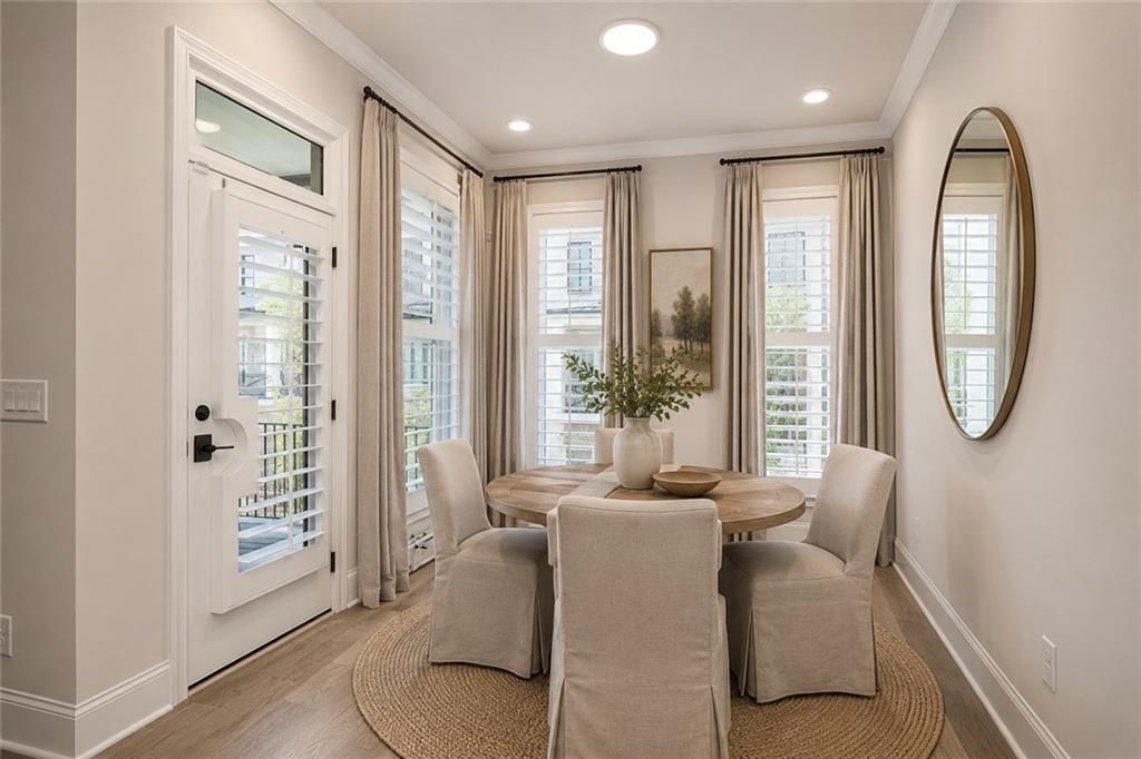 Breakfast nook with a round wood table, upholstered chairs, and tall shuttered windows.