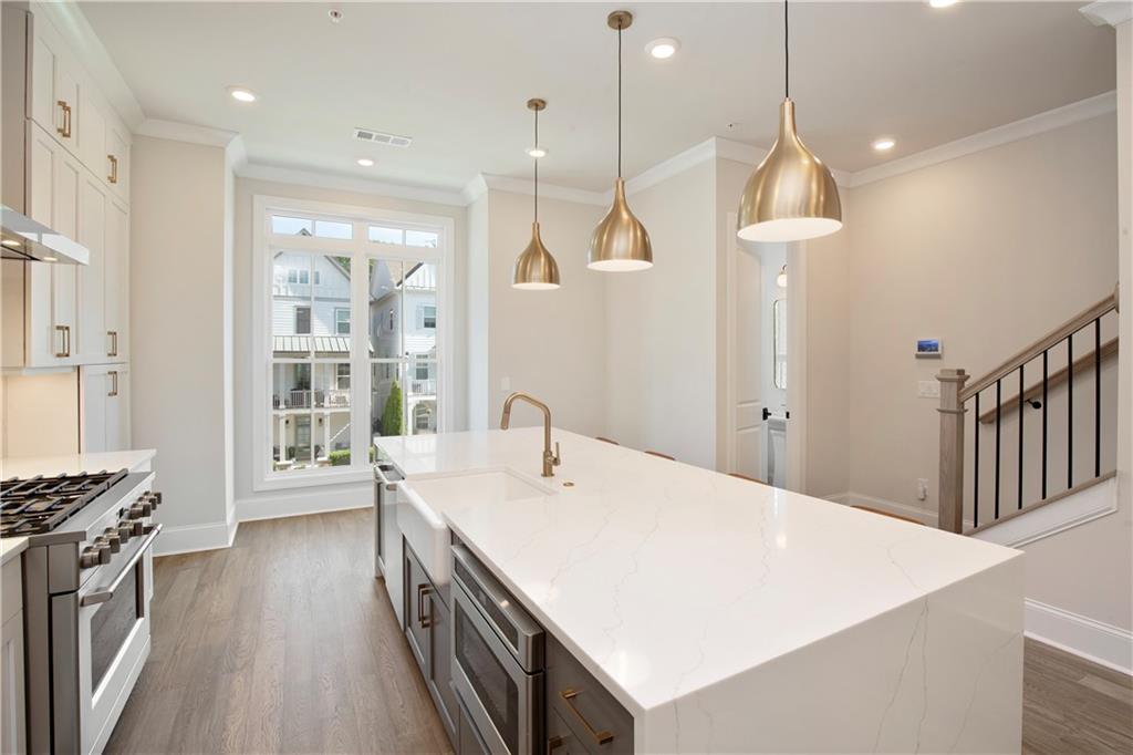 Modern kitchen with a large white quartz island, brass pendant lights, and a stainless steel gas range.