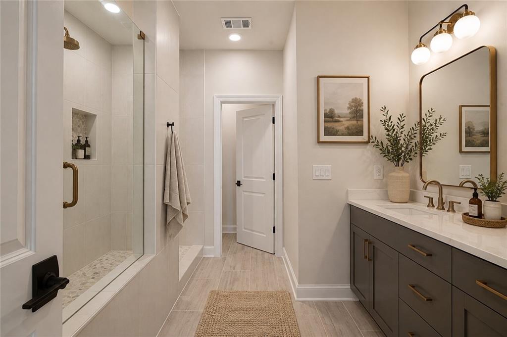 Bathroom with a glass walk-in shower and dark vanity with brass fixtures.