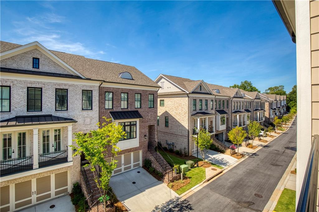 Attached brick and stone townhomes line a sunny residential street.