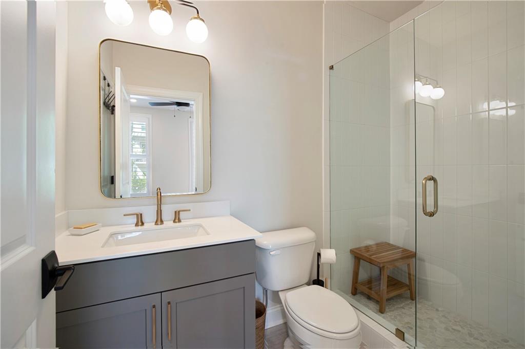 Bathroom with gray vanity, brass fixtures, and glass-enclosed tiled shower.