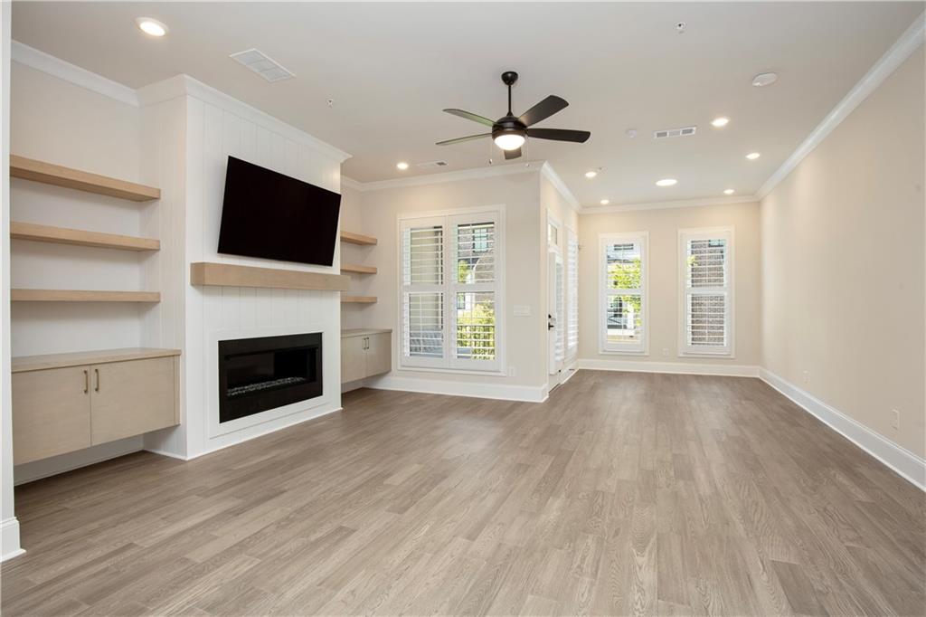 Unfurnished living room with built-in fireplace and shelving, mounted TV, and shuttered windows.