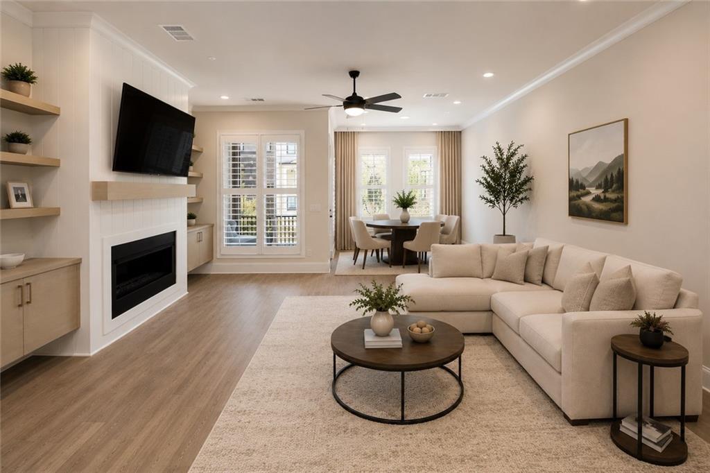 Living room with a white sectional, fireplace, and dining area beside large curtained windows.
