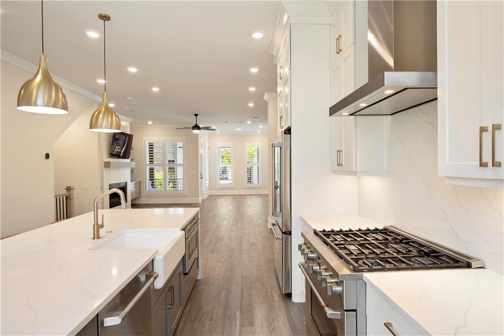 Modern kitchen with a marble-look island, brass pendants, and stainless steel appliances.