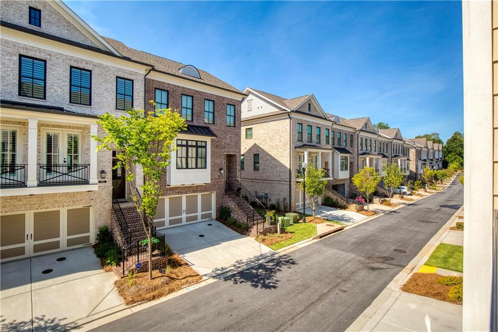 Attached townhouses with garages line a quiet street, framed by small trees and landscaped front yards.