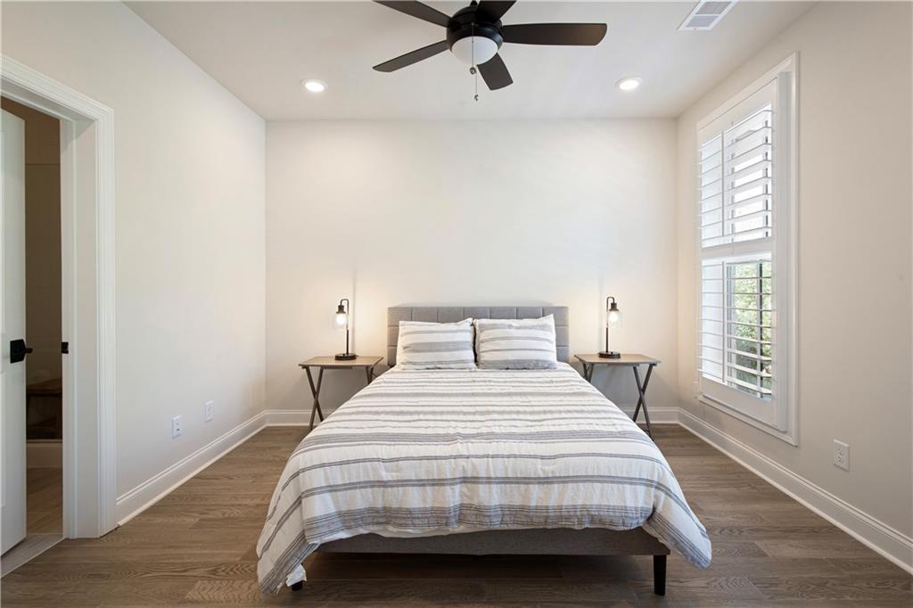 Bedroom with striped bedding, matching bedside tables, and a tall shuttered window.