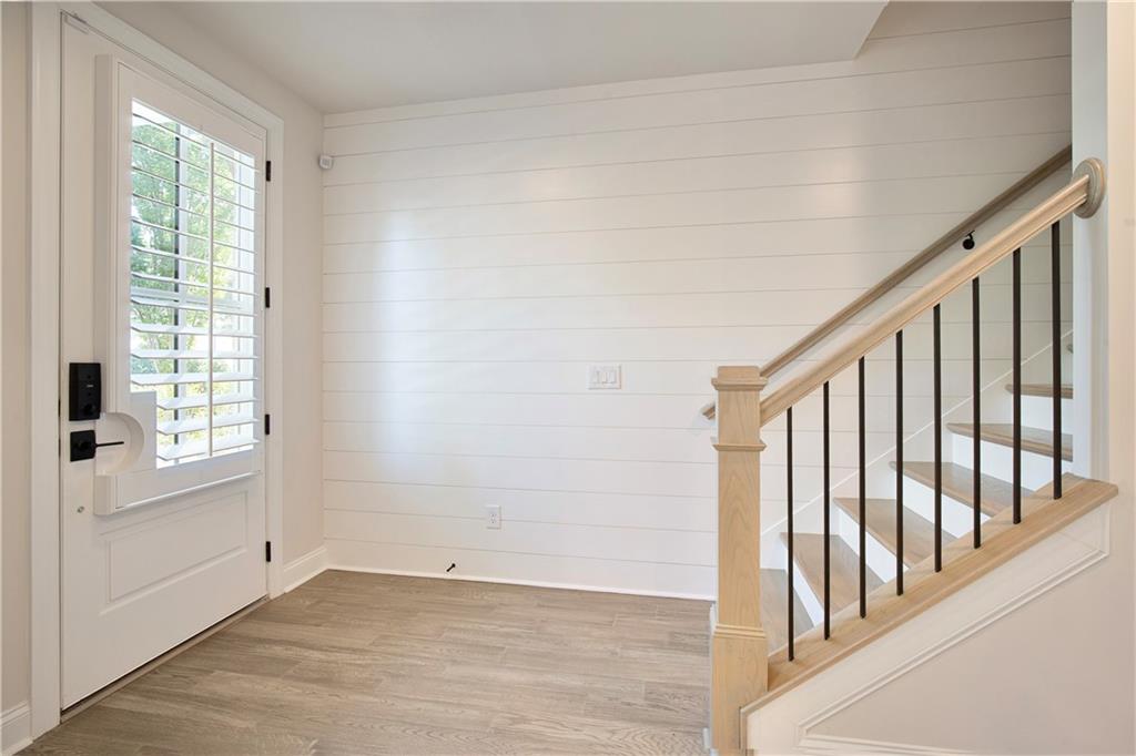 Vacant entry foyer with a shuttered front door and light wood staircase with black balusters.