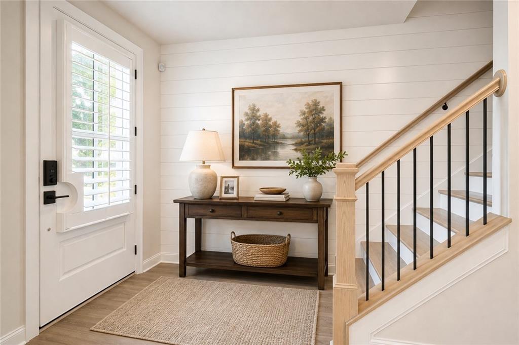 Entryway with a shuttered front door, console table, and wood-and-black-metal staircase.