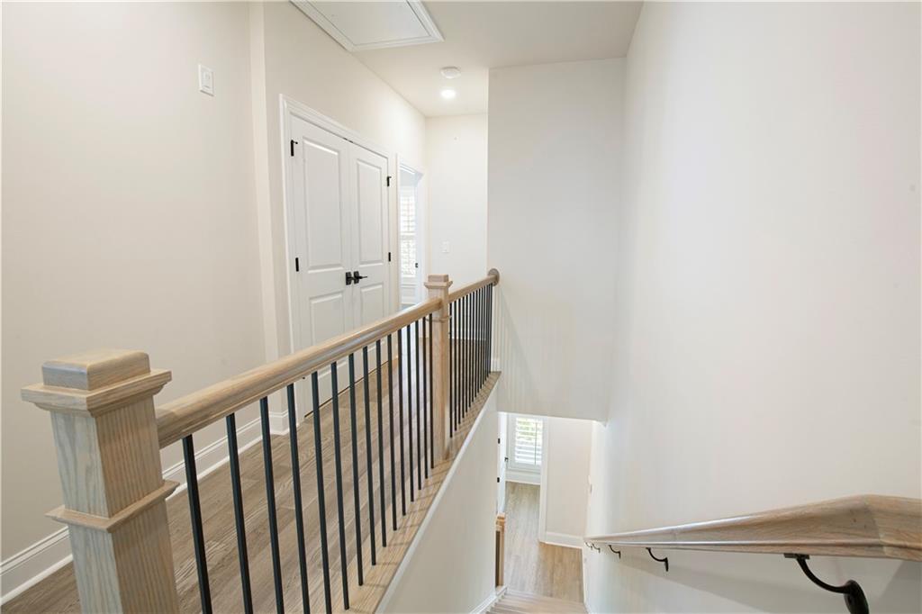 Staircase and upper landing with light wood rails, black balusters, and white paneled doors.