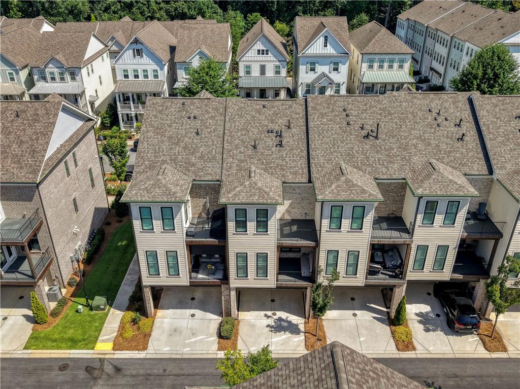 Aerial view of attached townhomes with small balconies and covered parking.