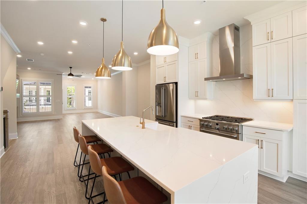 Open kitchen with a large white island, brass pendant lights, and stainless steel appliances.