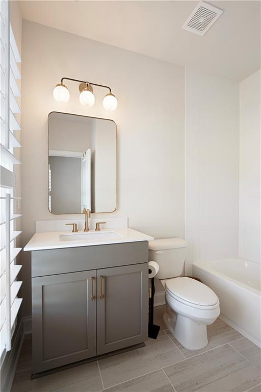 Bathroom with gray vanity, brass fixtures, white shutters, and a bathtub.