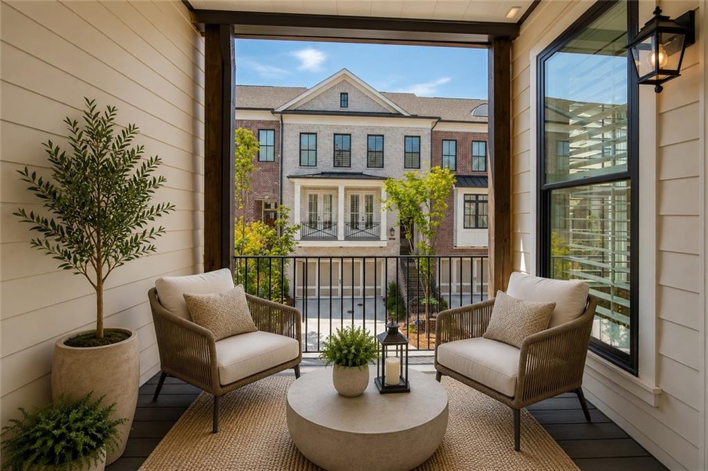 Covered porch with wicker seating and a round coffee table overlooking neighboring townhomes.