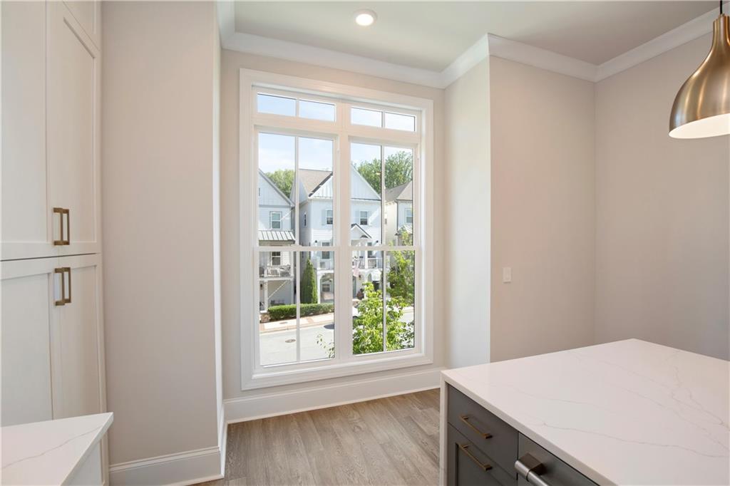 Modern kitchen with a stone island, white cabinetry, and a large window overlooking neighboring homes.