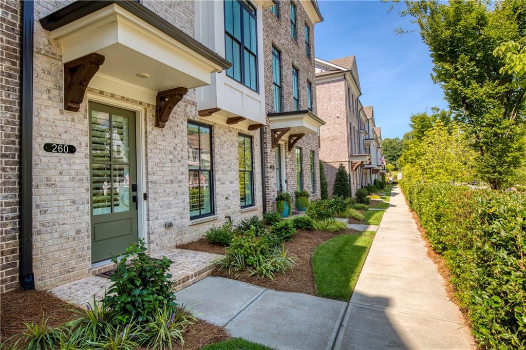 Brick townhome at 260 Briscoe Way with a green entry door, landscaped beds, and sidewalk.
