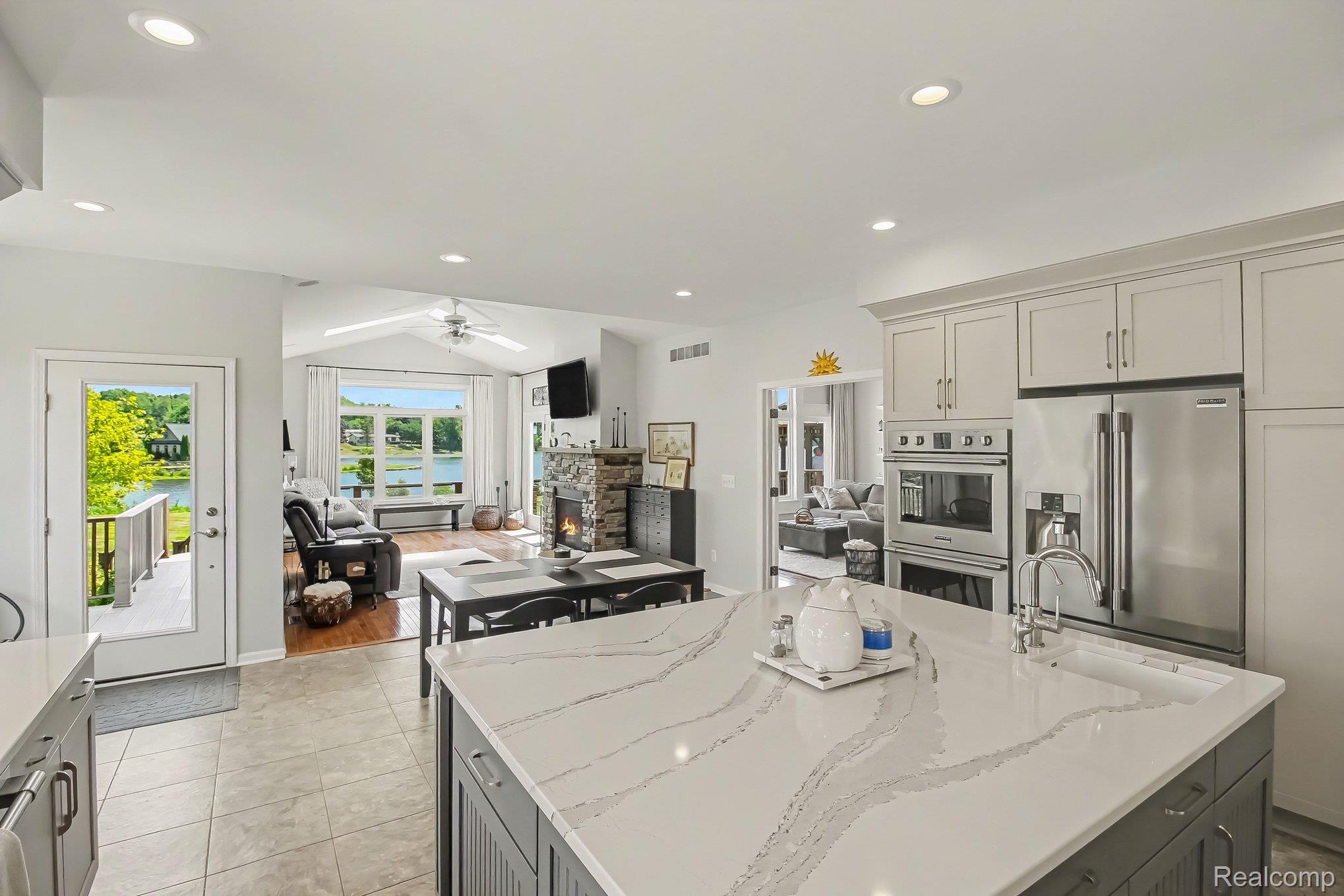 Kitchen with a large quartz island, stainless appliances, and lake views through the adjoining living room.
