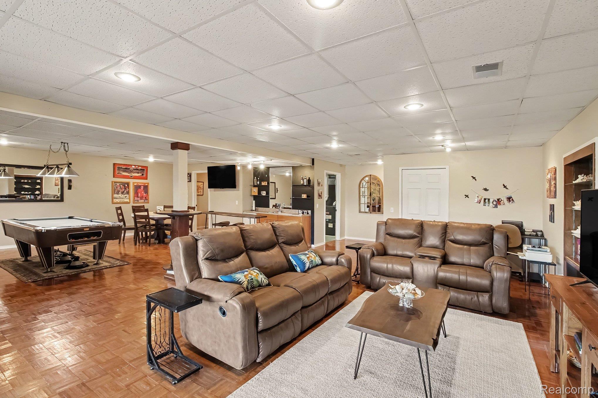Furnished recreation room with leather sofas, a pool table, and a dining area.