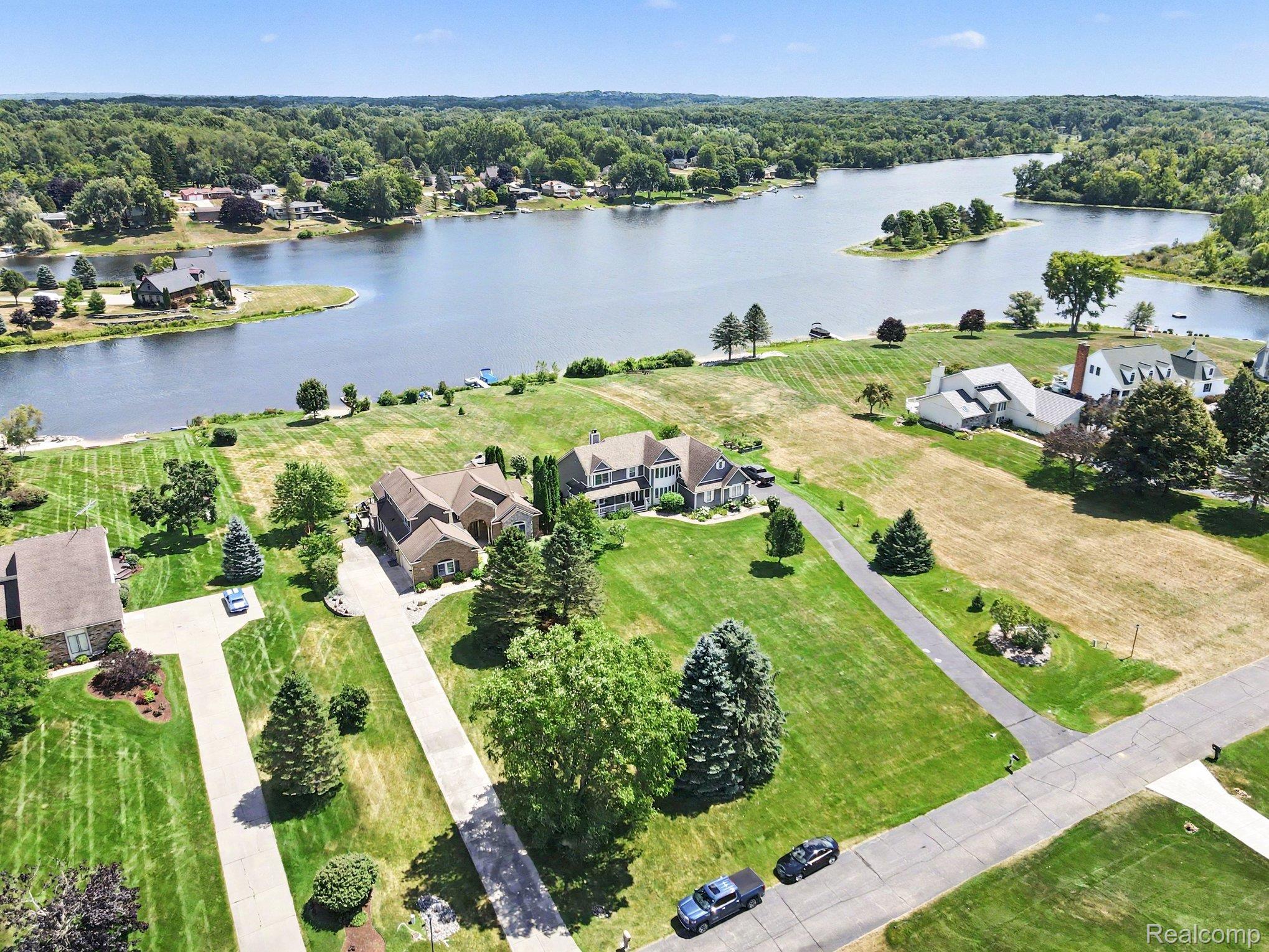 Aerial view of a large home beside a lake, with expansive lawns and a wooded shoreline.