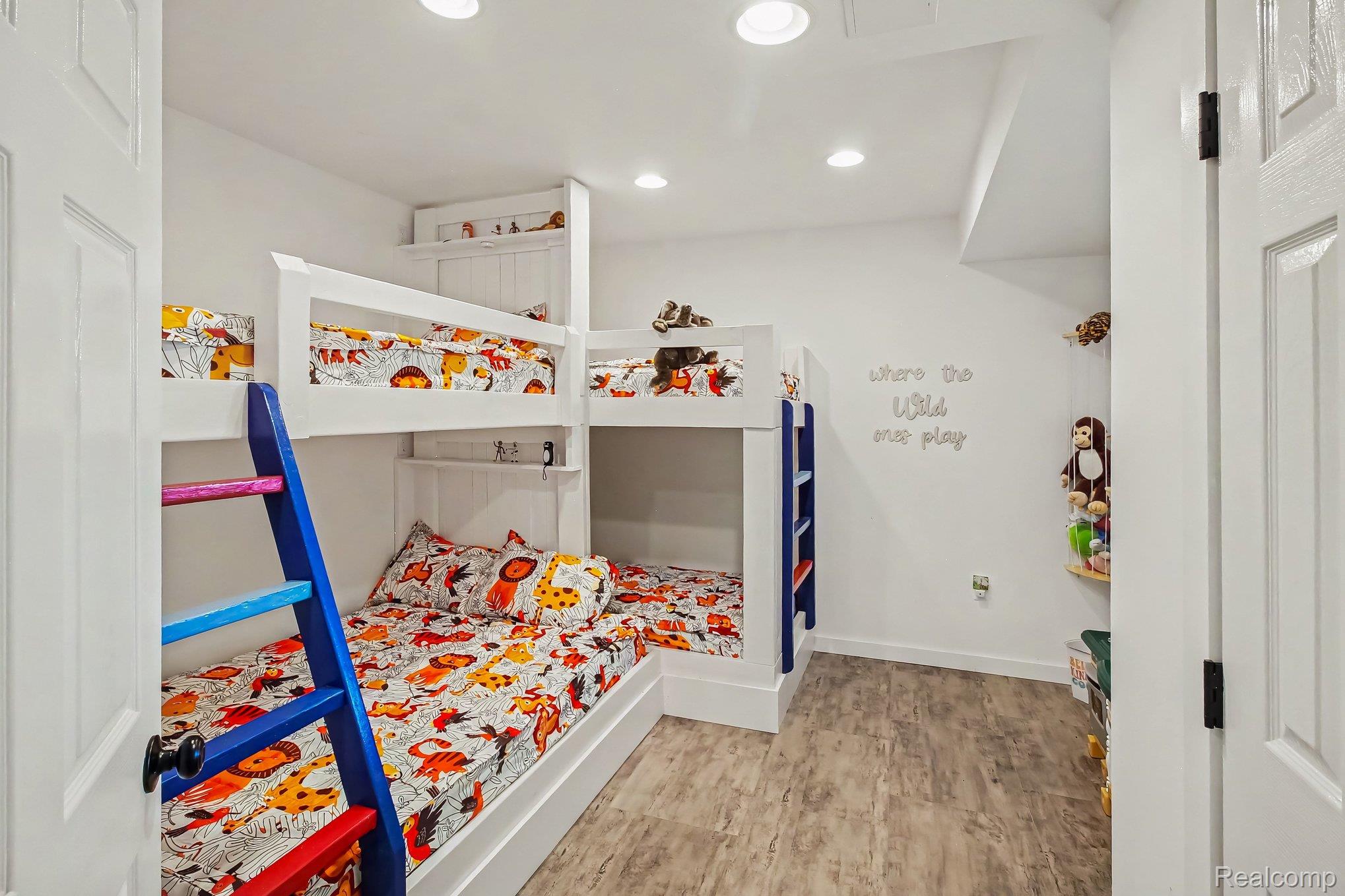 Children’s bedroom with colorful animal-print bunk beds and bright blue ladders.