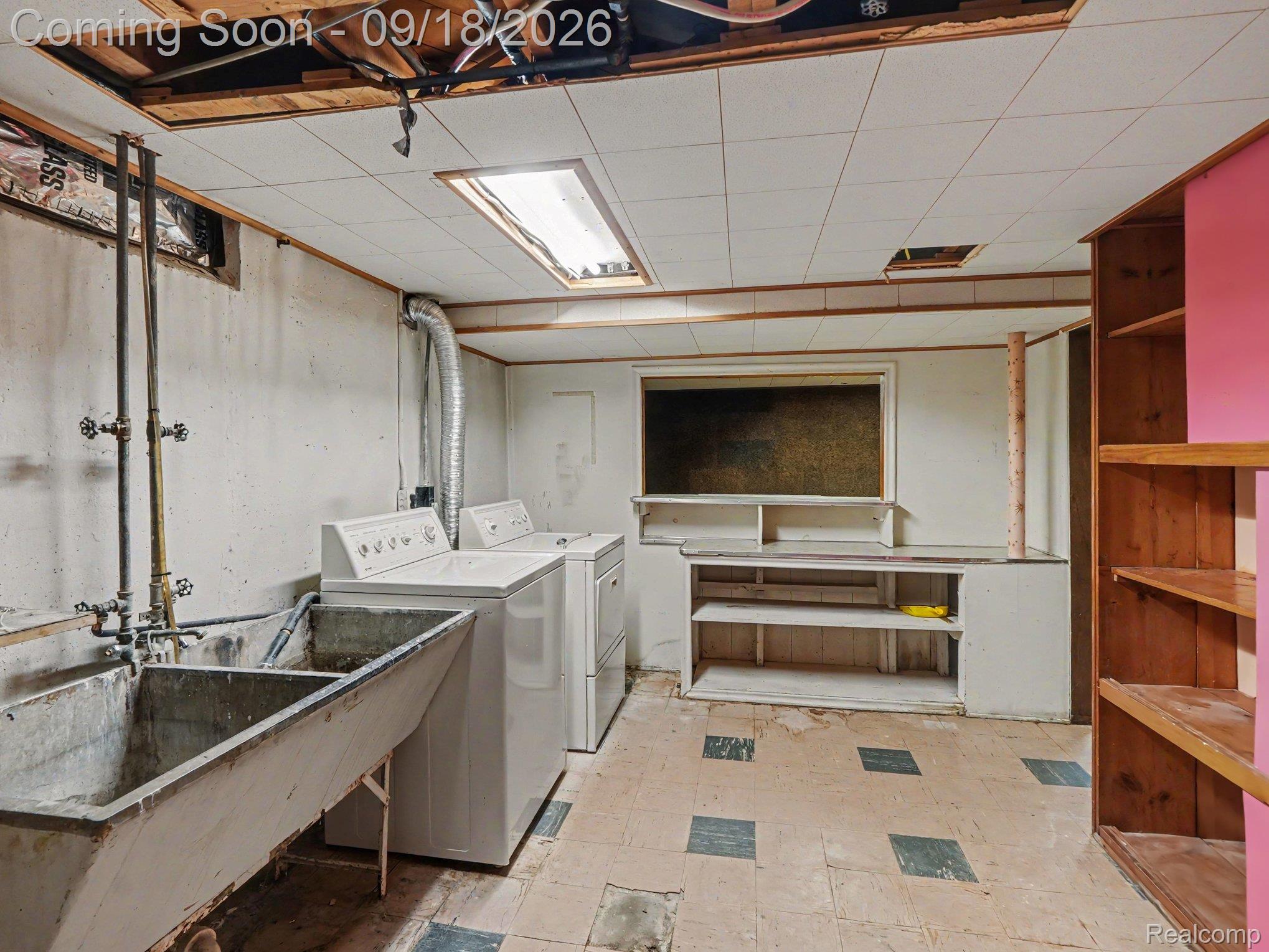 Basement laundry area with washer, dryer, large utility sink, and built-in workbench.