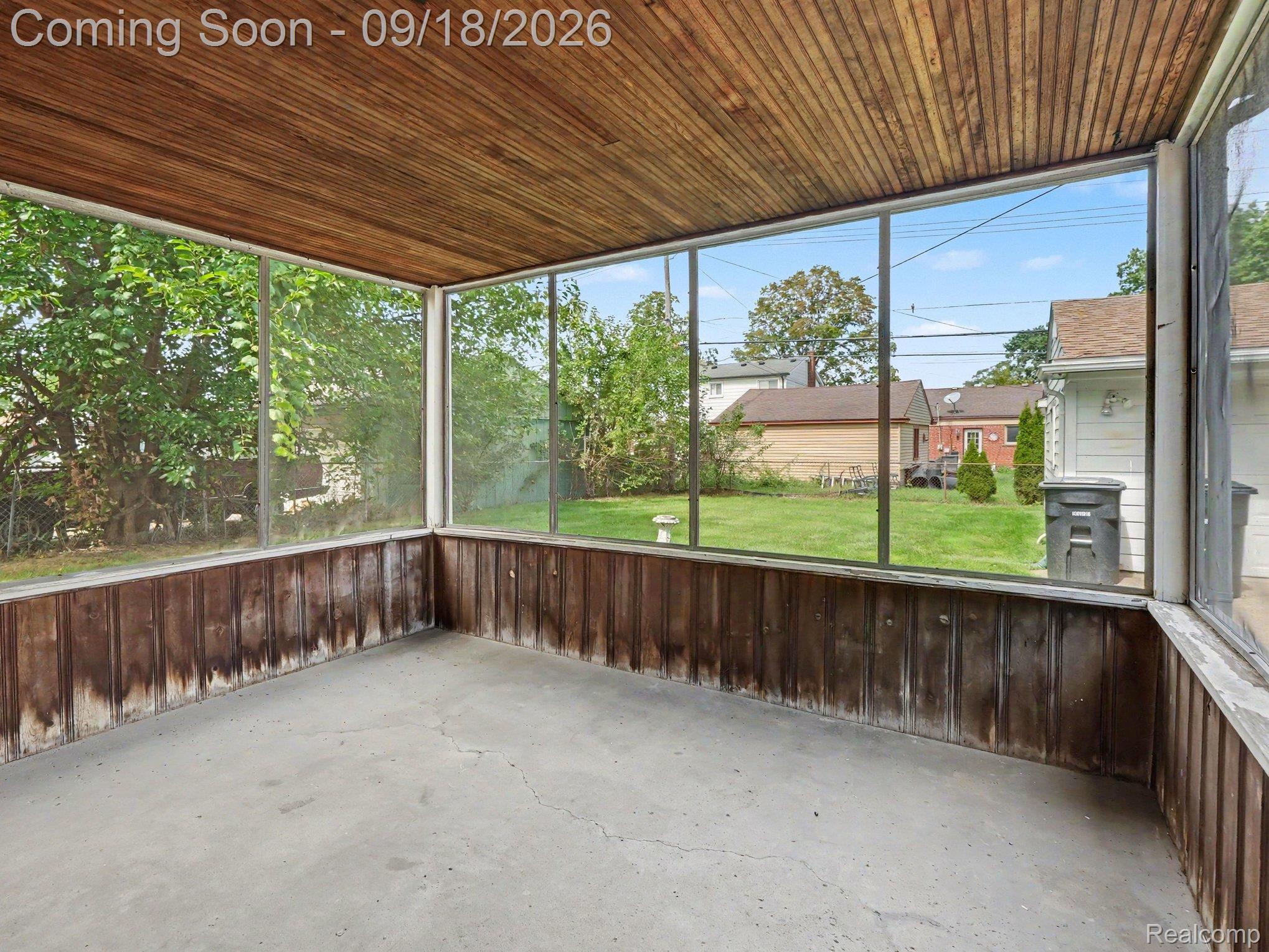 Enclosed porch with a wood-plank ceiling and wide windows overlooking the backyard.