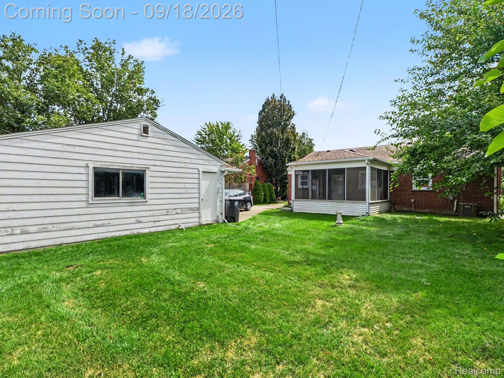 Backyard with a broad lawn, screened porch, and detached white garage.