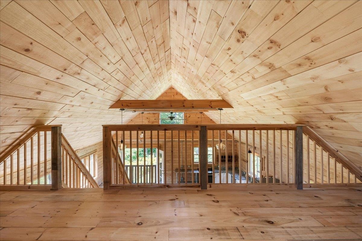 Wood-lined loft with a vaulted ceiling and railing overlooking the rooms below.