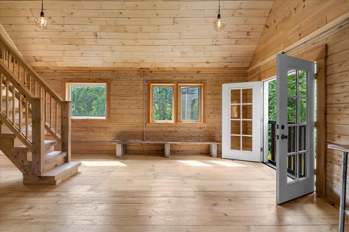 Wood-paneled interior with a staircase, built-in bench, and open glass-paneled door.