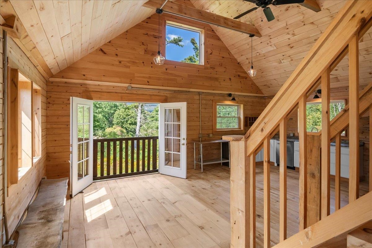 Wood-paneled loft with vaulted ceiling, staircase, and open French doors to a balcony.