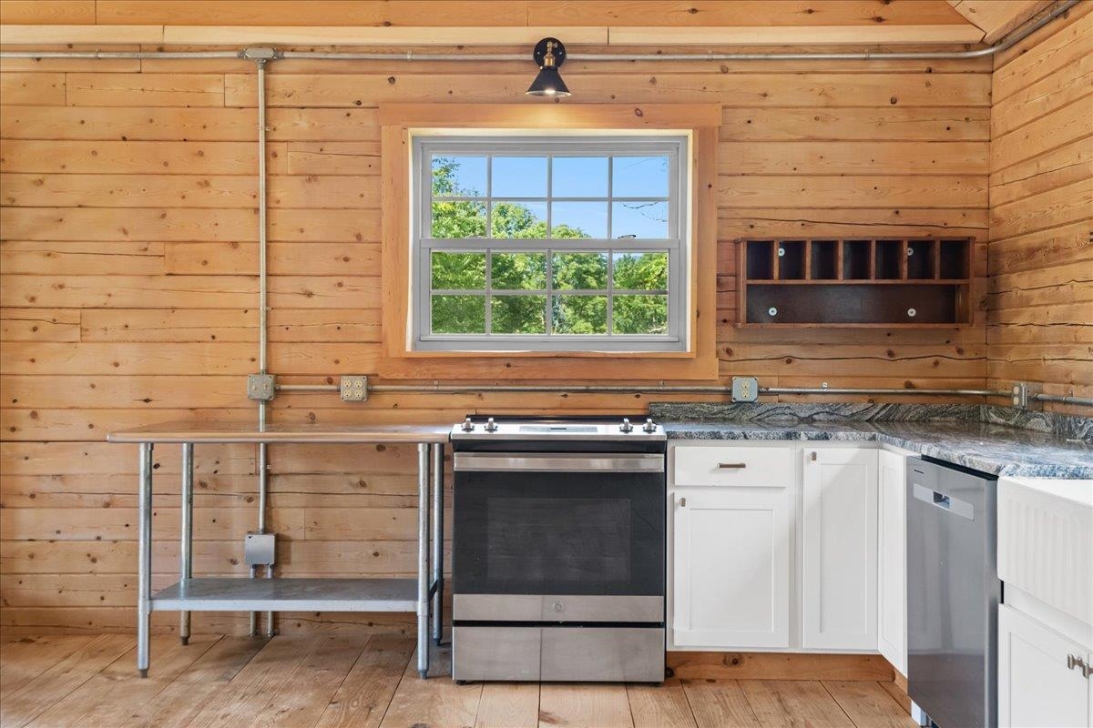 Wood-paneled kitchen with stainless steel appliances, granite counters, and a window overlooking trees.