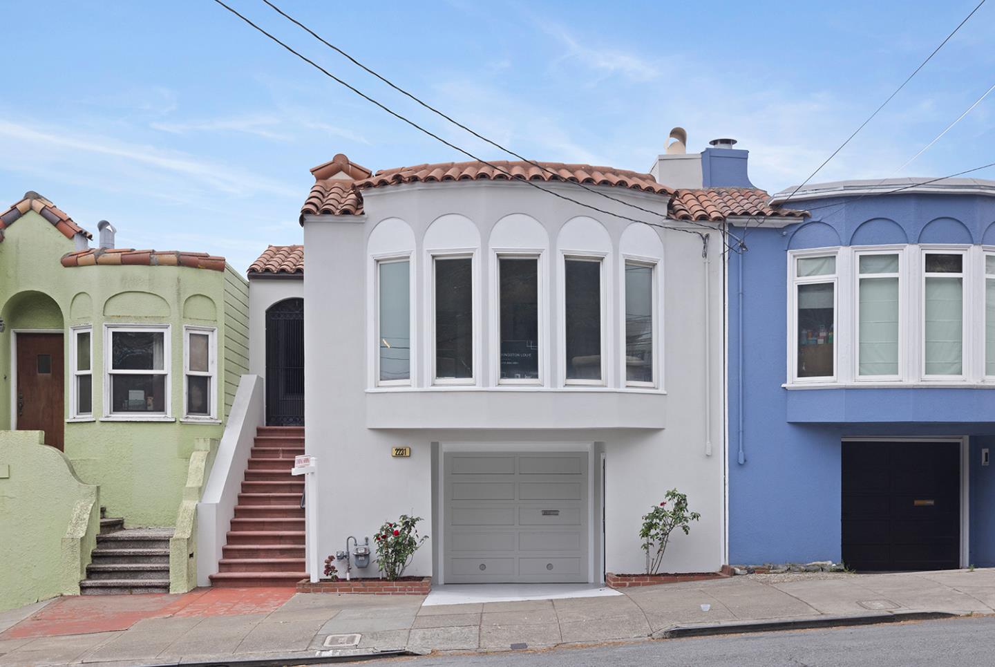 White San Francisco home with a terracotta tile roof, arched-top windows, and a ground-floor garage.
