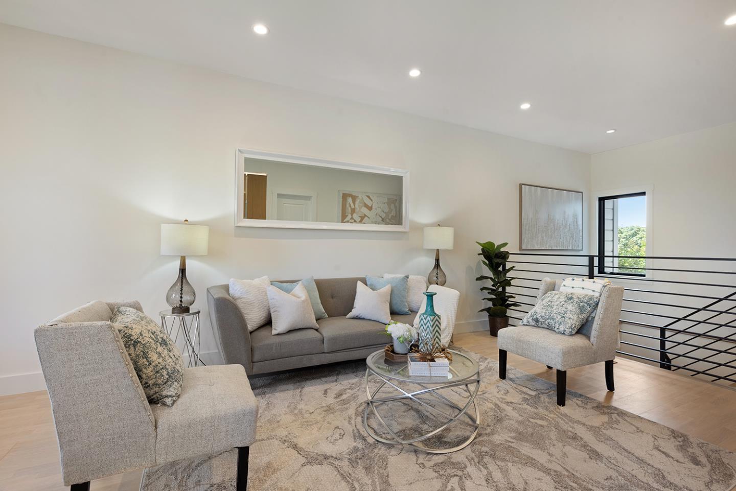 Staged living room with a gray sofa, upholstered armchairs, and round glass coffee table.