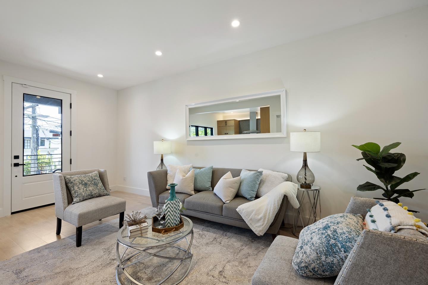 Staged living room with gray seating, a glass coffee table, and a balcony door.