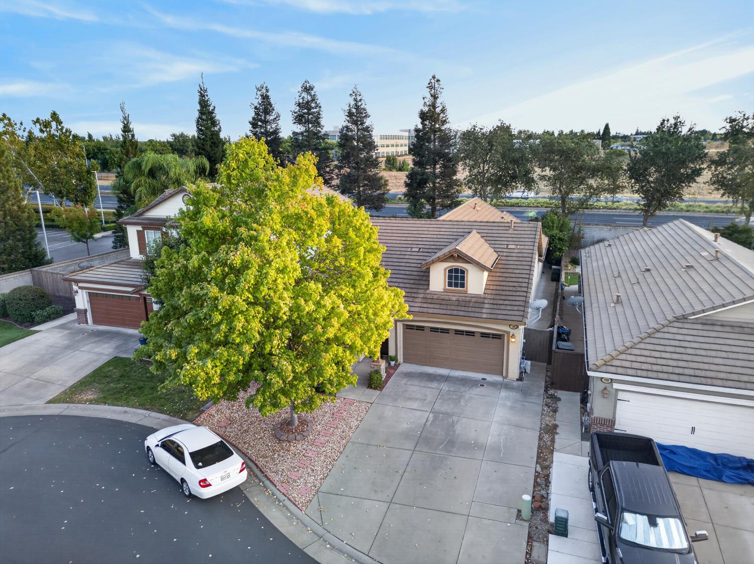 Aerial view of a two-story home with a large yellow-leaved tree and attached garage.