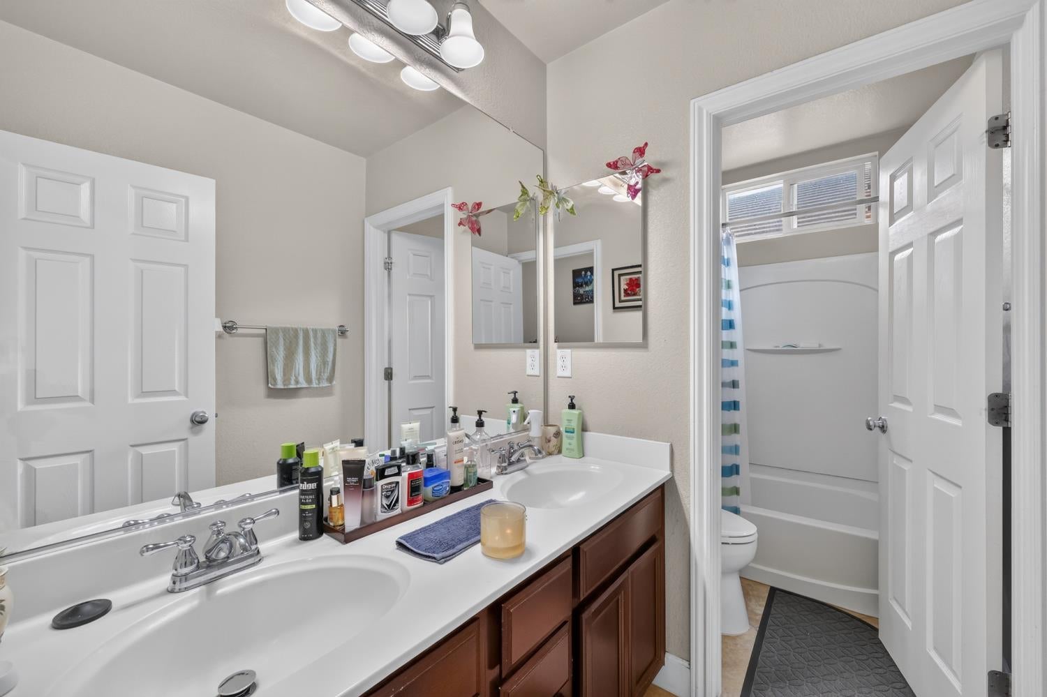 Bathroom with a double-sink vanity and mirror beside a tub and shower.