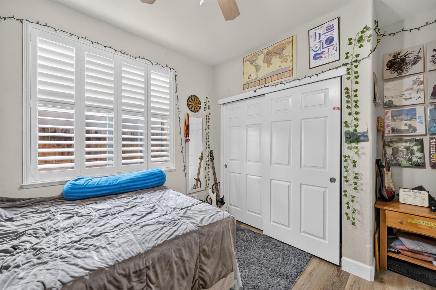 Bedroom with white plantation shutters, sliding closet doors, guitars, and wall art.